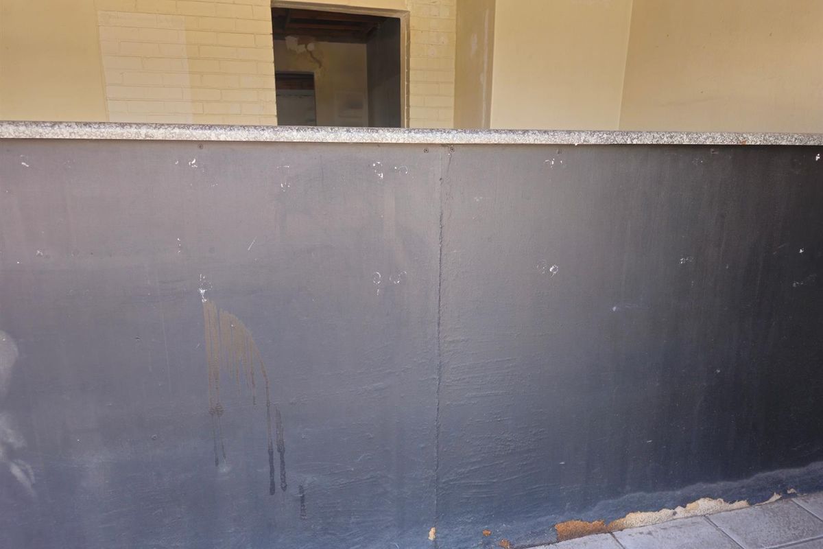 A commercial kitchen service counter featuring a stone top, currently in need of cosmetic repairs and finishing to the surrounding wall and base.