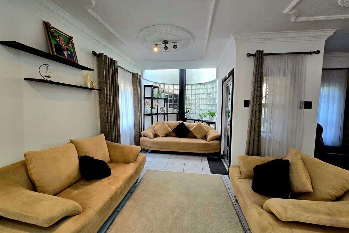 A living room featuring decorative ceiling cornices, a central ceiling rose, and a distinctive glass block feature wall providing natural light.