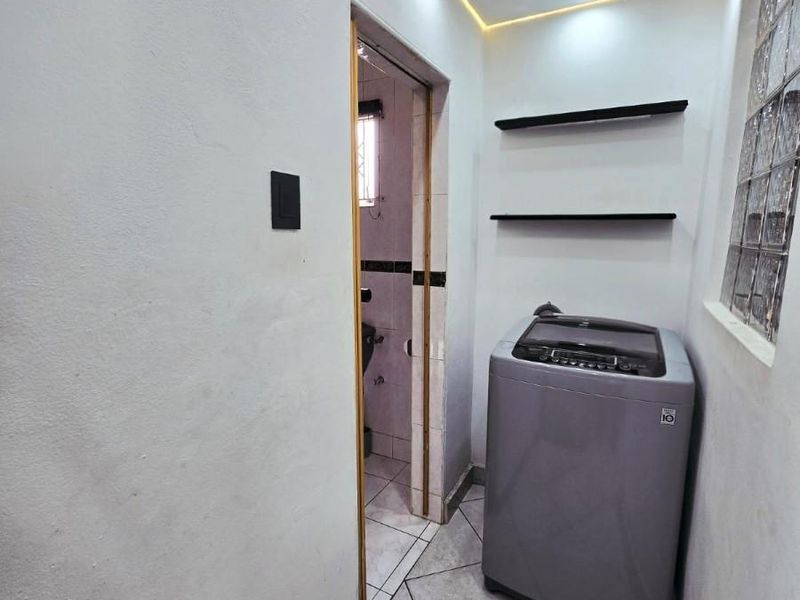 A functional laundry area featuring tiled flooring, recessed ceiling lighting with ambient strip lighting, and built-in wall shelving.