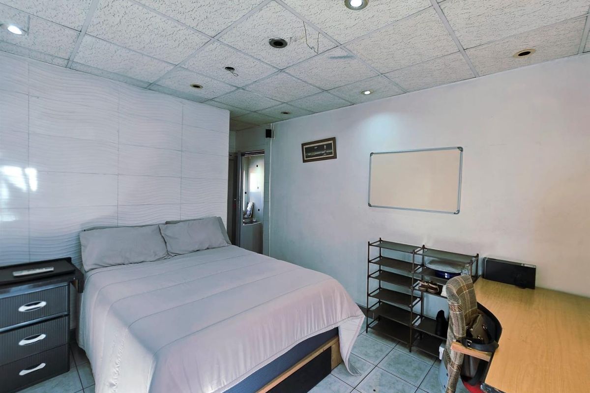 A bedroom featuring a textured accent wall, tiled flooring, and a drop ceiling with recessed lighting.