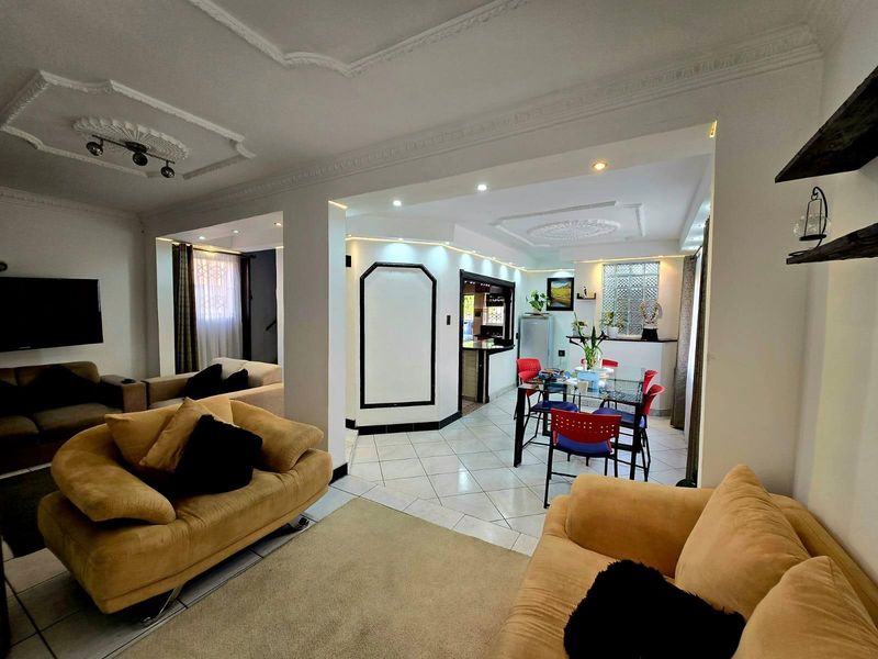 Open-plan living and dining area featuring decorative ceiling moldings, recessed lighting, and tiled flooring, creating a connected and functional living space.
