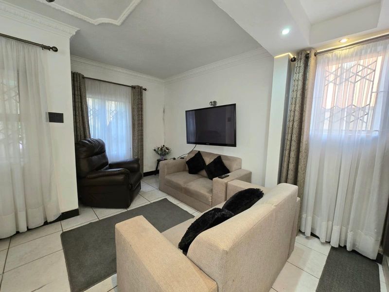 A bright living room featuring tiled flooring, decorative ceiling cornices, and large windows with integrated security bars.