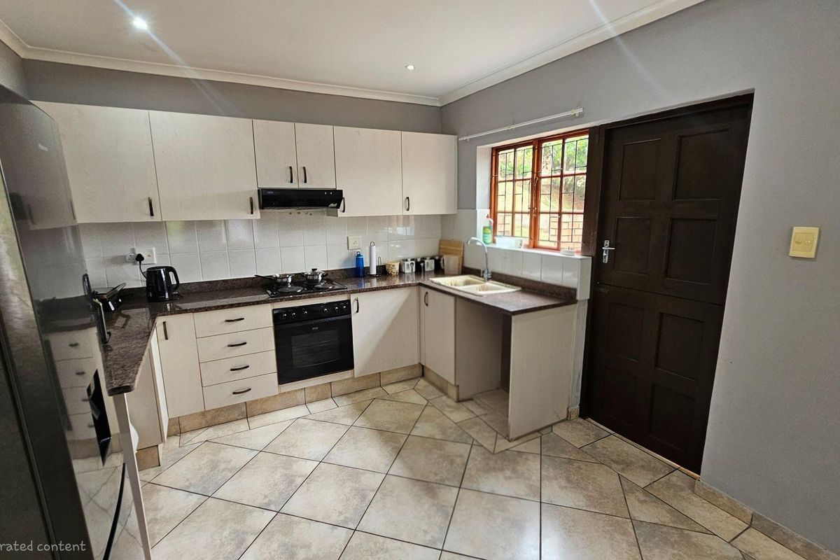 Functional kitchen featuring built-in cabinetry, integrated oven and hob, double sink, and tiled flooring with direct access to the exterior.