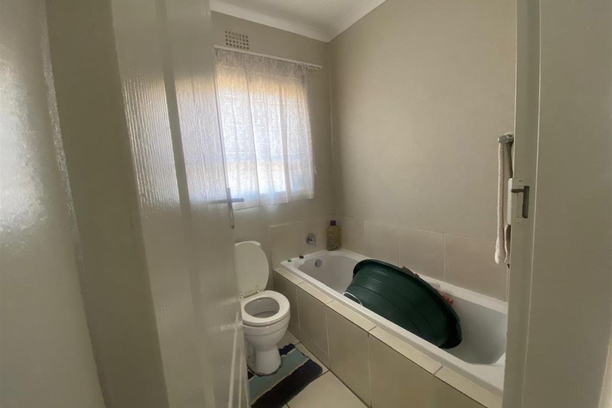 A functional bathroom featuring a built-in bathtub with tiled surround and a standard toilet.