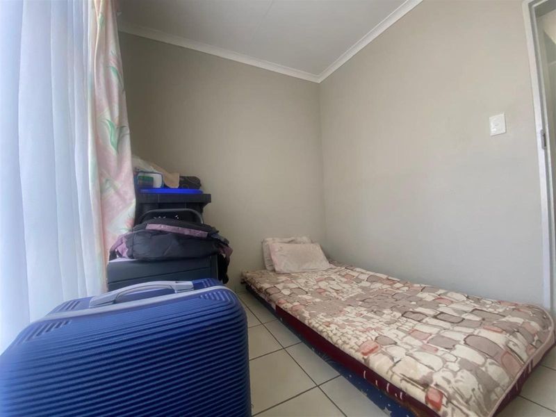 A compact bedroom featuring tiled flooring and neutral wall finishes, suitable for a single bed setup.