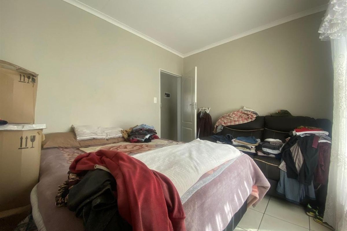 A bedroom featuring tiled flooring and neutral wall finishes, providing a functional space for rest.