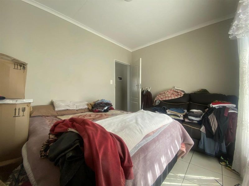 A bedroom featuring tiled flooring and neutral wall finishes, providing a functional space for rest.
