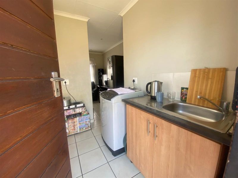 A functional laundry area featuring a stainless steel sink, built-in cabinetry, and tiled flooring, providing convenient utility space.