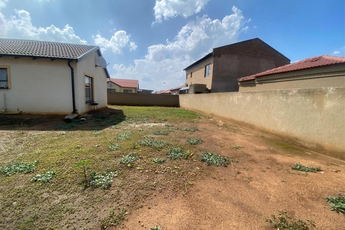 A spacious rear garden area featuring a perimeter boundary wall and direct access to the side of the house.
