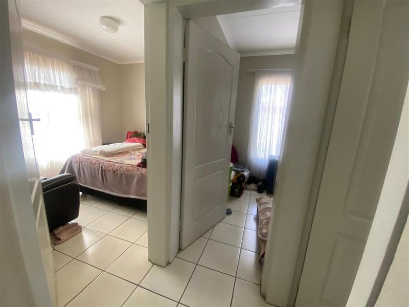A view from a hallway looking into two separate bedrooms, featuring tiled flooring and standard interior doors.