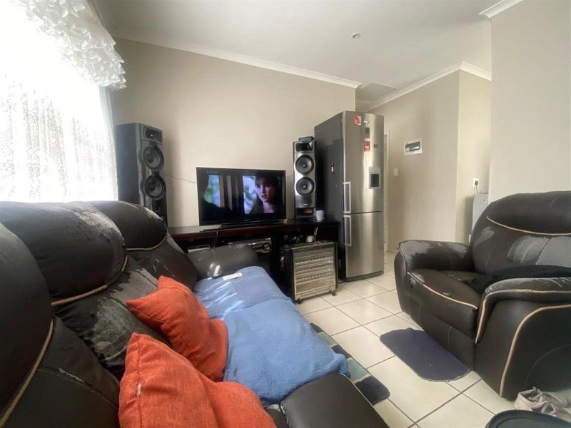 A living area featuring tiled flooring and neutral wall finishes, providing a functional space for relaxation.