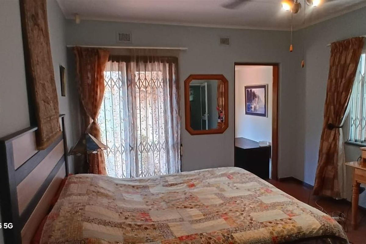 A bedroom featuring a ceiling fan, air conditioning unit, and sliding glass doors with security gates leading to the exterior.