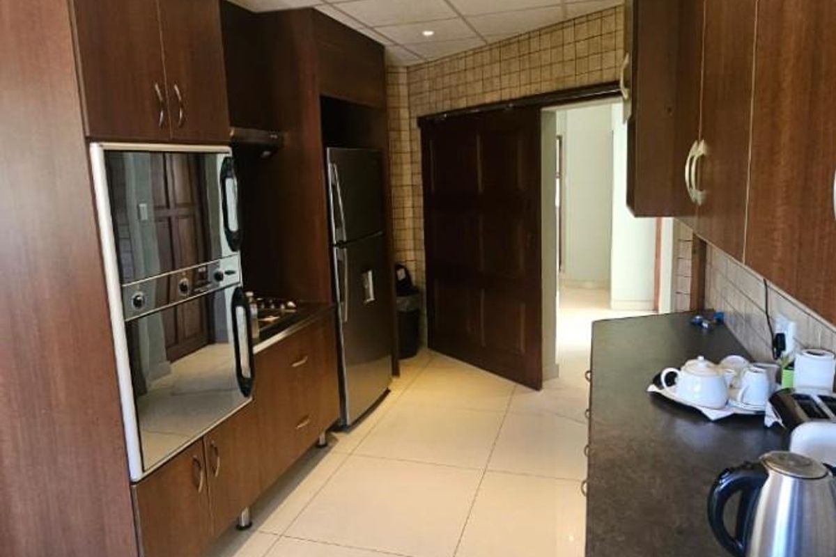 A functional kitchen featuring dark wood cabinetry, built-in oven, tiled flooring, and recessed ceiling lighting, providing a practical workspace.