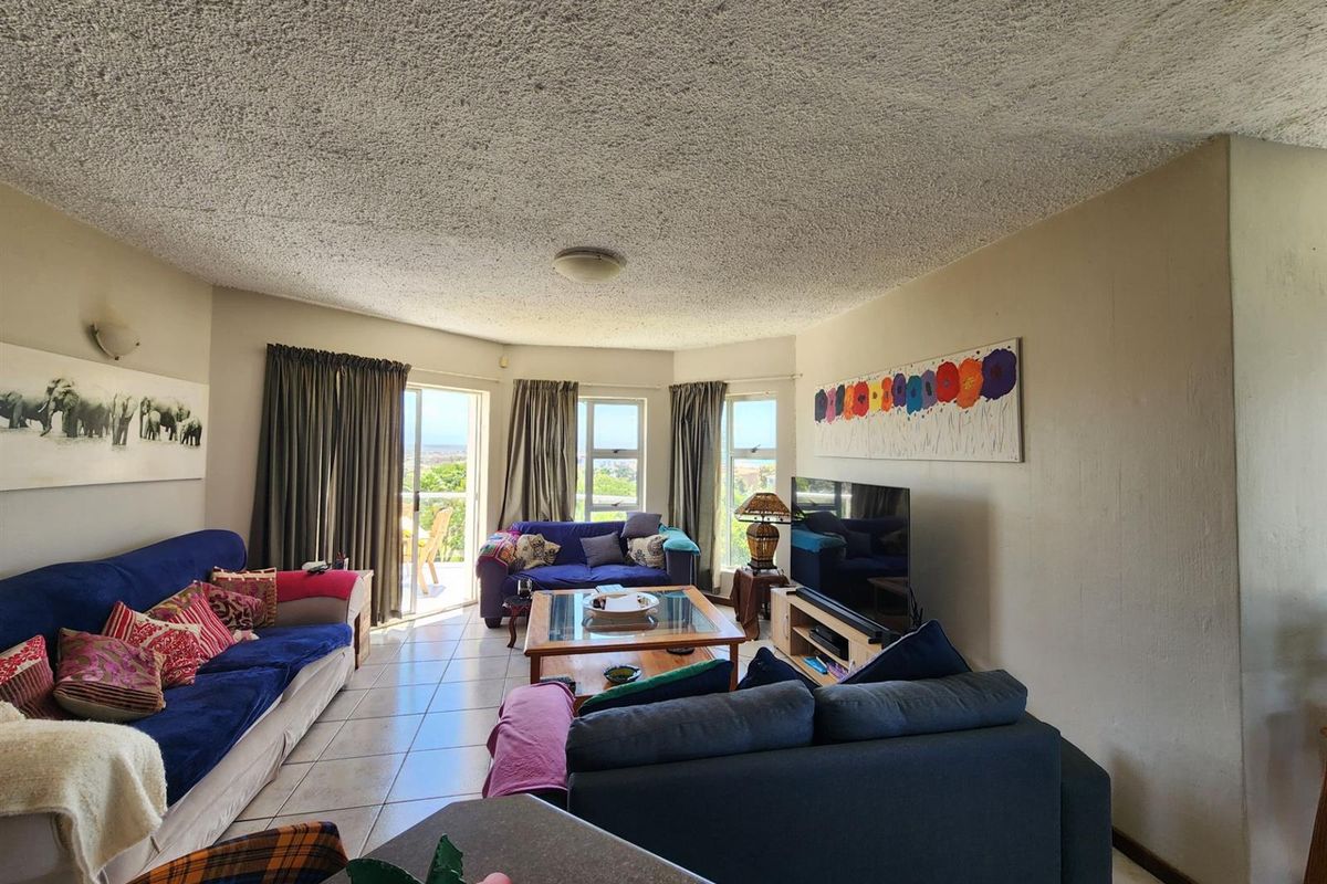 Spacious living room featuring tiled flooring, large windows, and sliding glass doors leading to an outdoor balcony area.