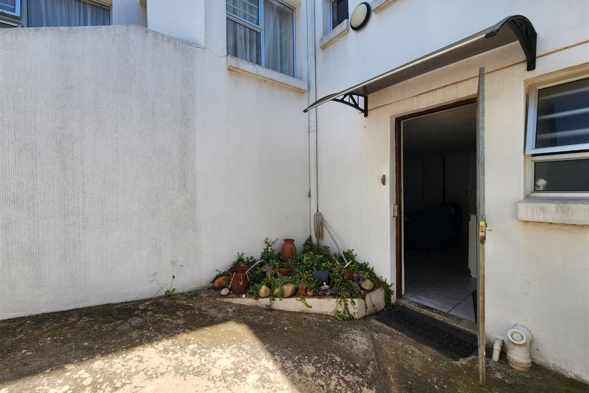 A small, paved rear courtyard area featuring a built-in planter bed and direct access to the interior of the home.
