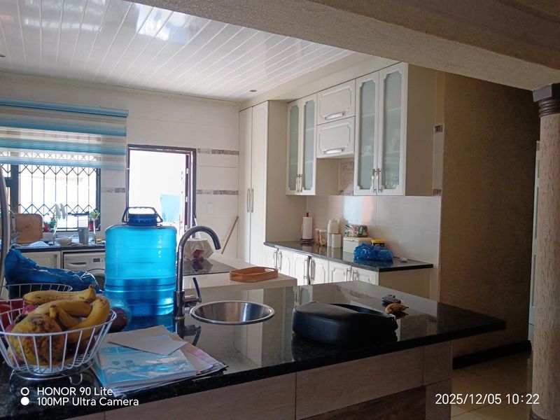A functional kitchen featuring granite countertops, ample built-in cabinetry, and a modern sink, offering a clean and practical workspace.