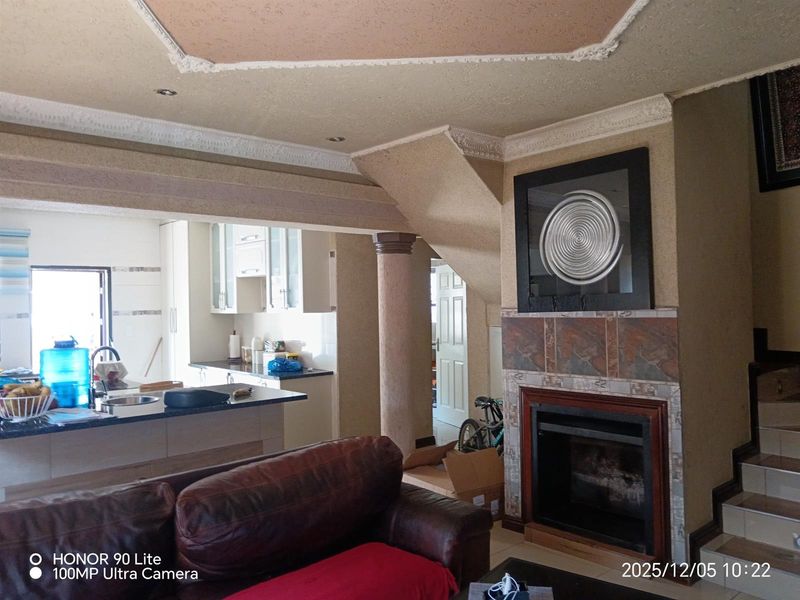 Open plan living area featuring a built-in fireplace with stone surround, integrated kitchen cabinetry, and decorative ceiling details.