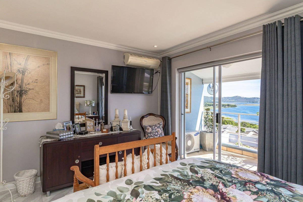 Spacious bedroom featuring large sliding glass doors that open onto a private balcony with scenic water views and integrated air conditioning.