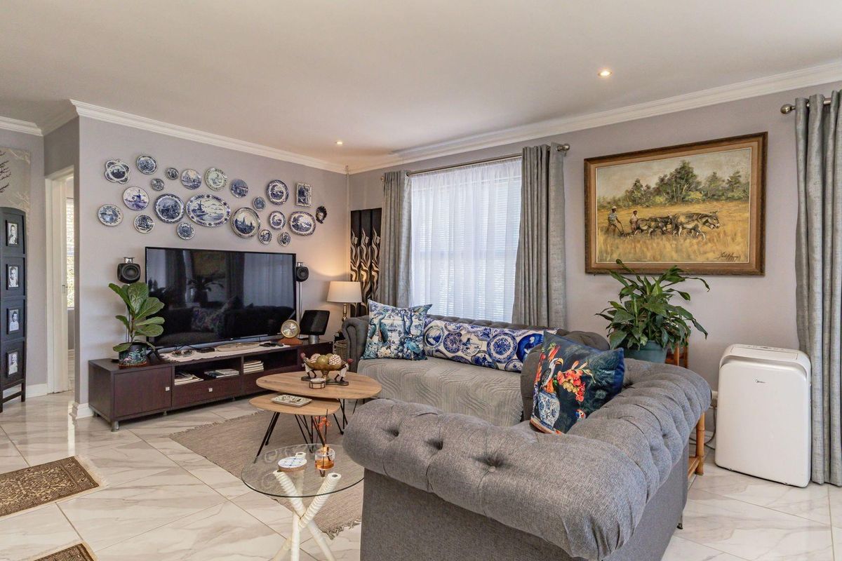A well-maintained living room featuring polished marble-look floor tiles, recessed downlighting, and crown molding, creating a bright and comfortable living space.
