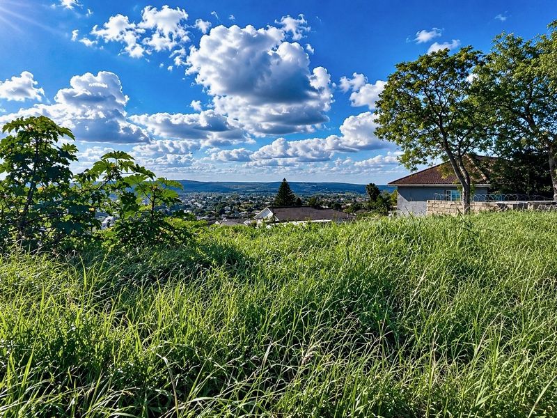 An elevated view overlooking the surrounding landscape and distant urban area from the vacant residential property.