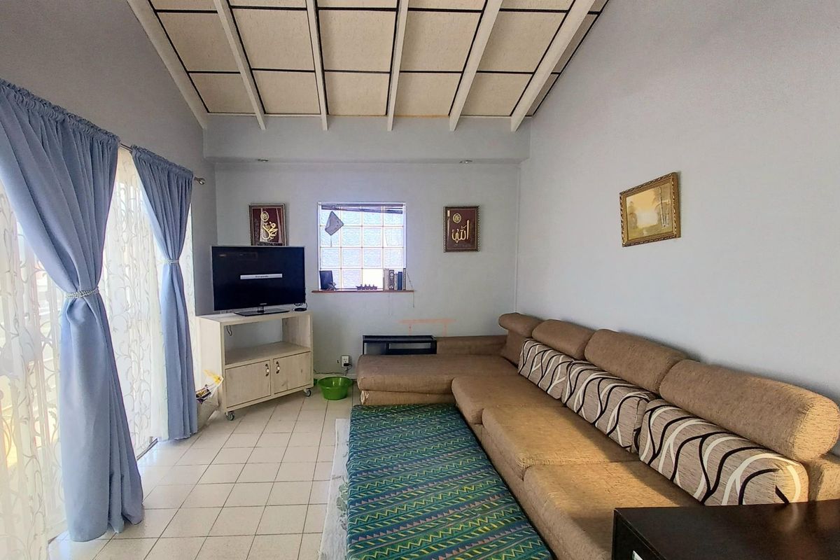 A living room featuring tiled flooring and a distinctive exposed beam ceiling with panel inserts, providing a functional and lived-in space.