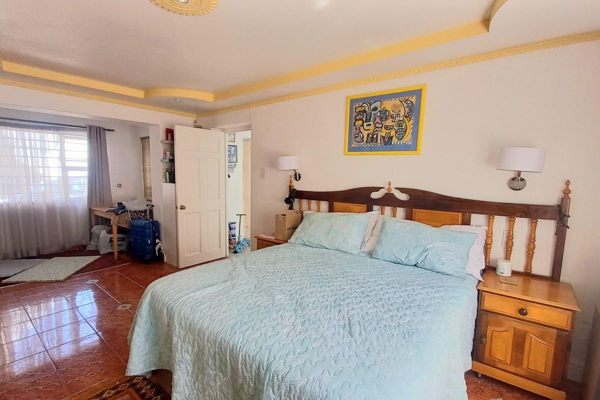 Spacious bedroom featuring tiled flooring, decorative ceiling molding, and an integrated layout with an adjacent alcove area.