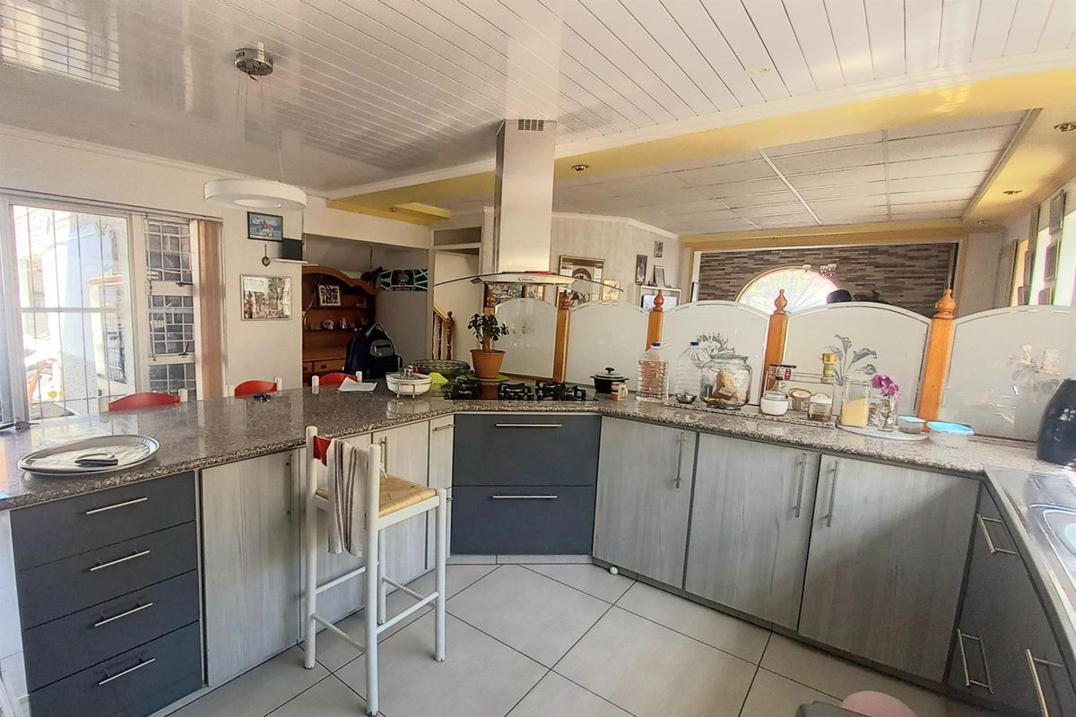 Spacious kitchen featuring a large granite-topped breakfast bar, built-in gas hob with extractor fan, and ample cabinetry for storage.