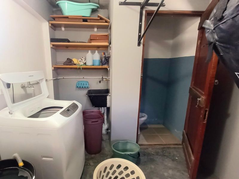 Utility space featuring a laundry area with built-in shelving, a utility sink, and an adjacent small bathroom.