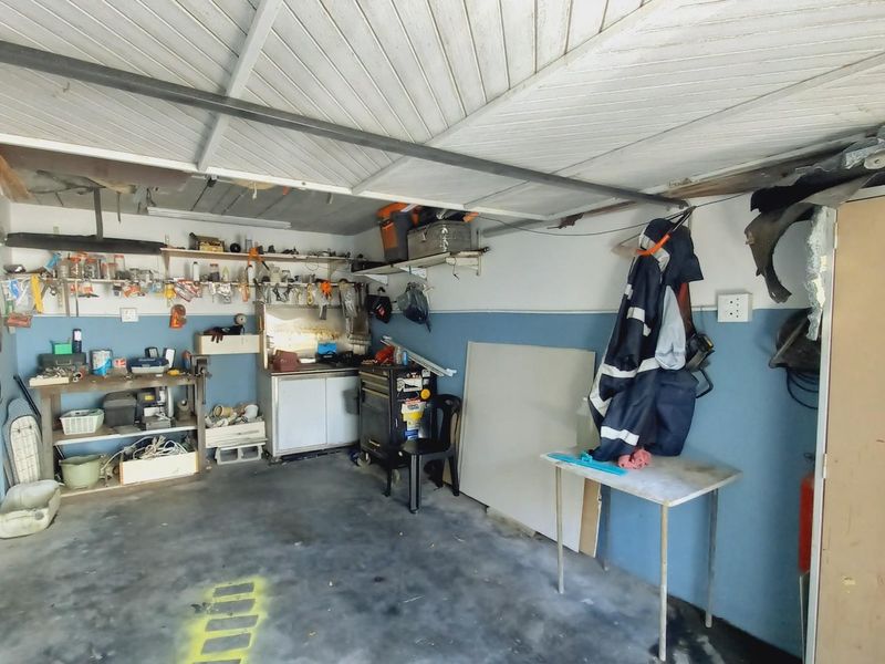 A functional garage space featuring built-in shelving, concrete flooring, and exposed ceiling panels, suitable for storage or workshop use.