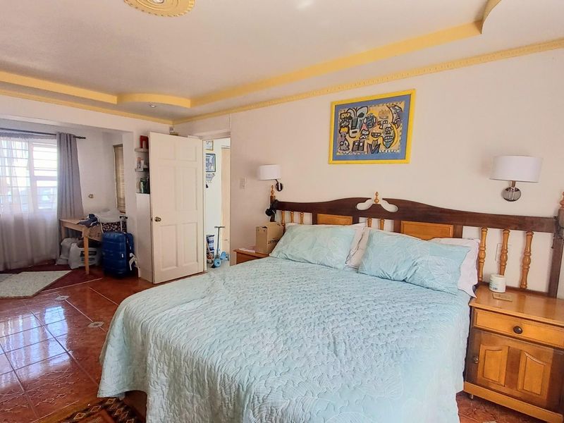 Spacious bedroom featuring tiled flooring, decorative ceiling molding, and an integrated layout with an adjacent alcove area.