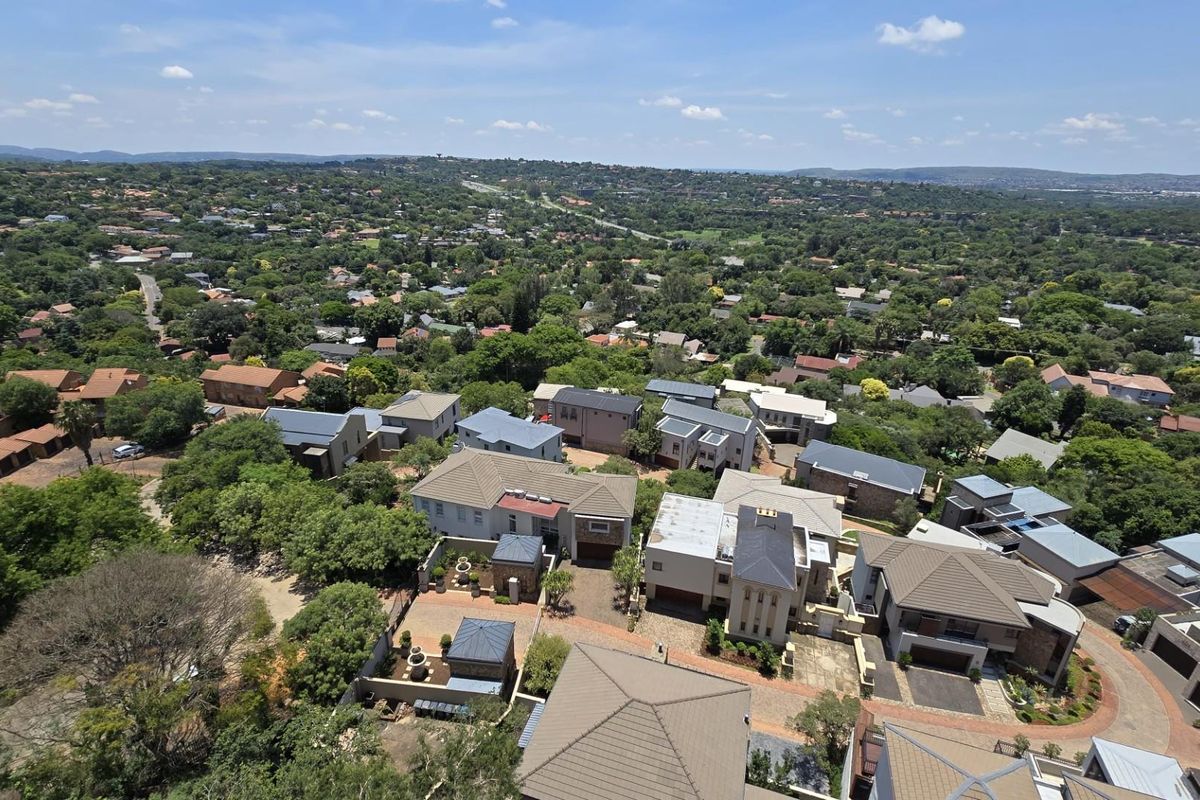 An elevated aerial view showcasing the surrounding residential neighborhood and lush green landscape from the penthouse perspective.