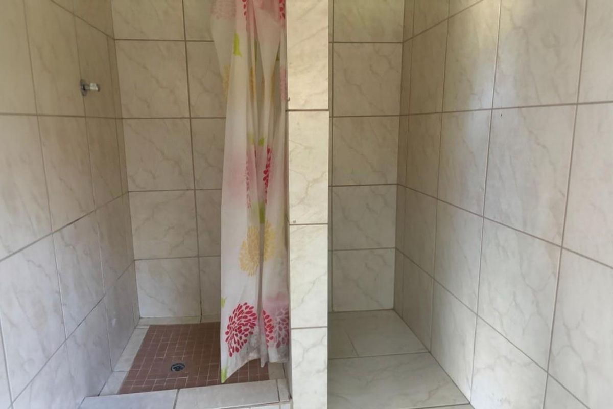A functional dual-stall shower area featuring tiled walls and flooring, requiring minor cosmetic updates to modernize the space.