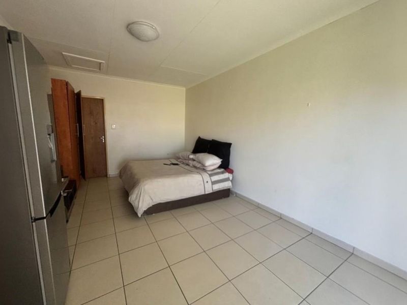 A simple bedroom featuring tiled flooring and a built-in cupboard, offering a functional and neutral space ready for personalization.