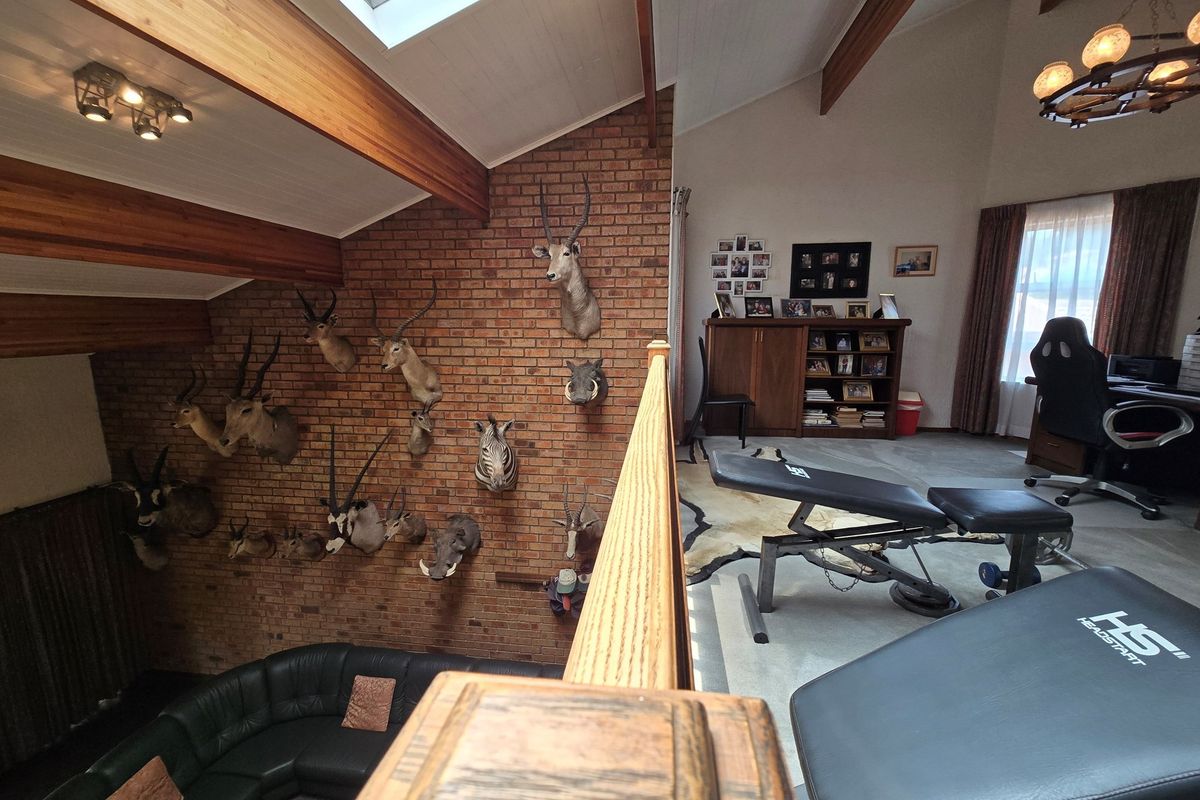 A multi-level living area featuring a prominent exposed brick feature wall, vaulted timber-beamed ceilings, and a mezzanine-style layout overlooking the lower level.
