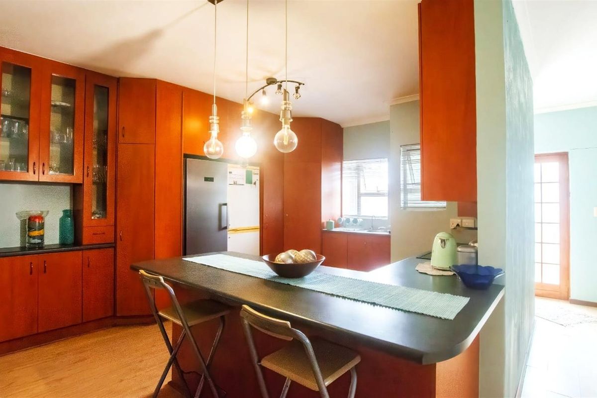 A functional kitchen featuring warm-toned wooden cabinetry, a breakfast bar island, and integrated storage, providing a practical layout for daily meal preparation.