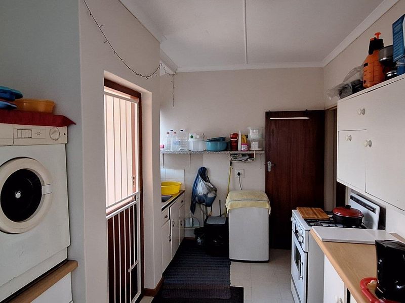 A functional laundry and scullery area featuring built-in cabinetry, a stove, and direct access to an exterior door.