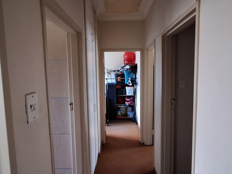 A functional interior hallway featuring built-in storage cupboards, providing access to multiple rooms within the home.