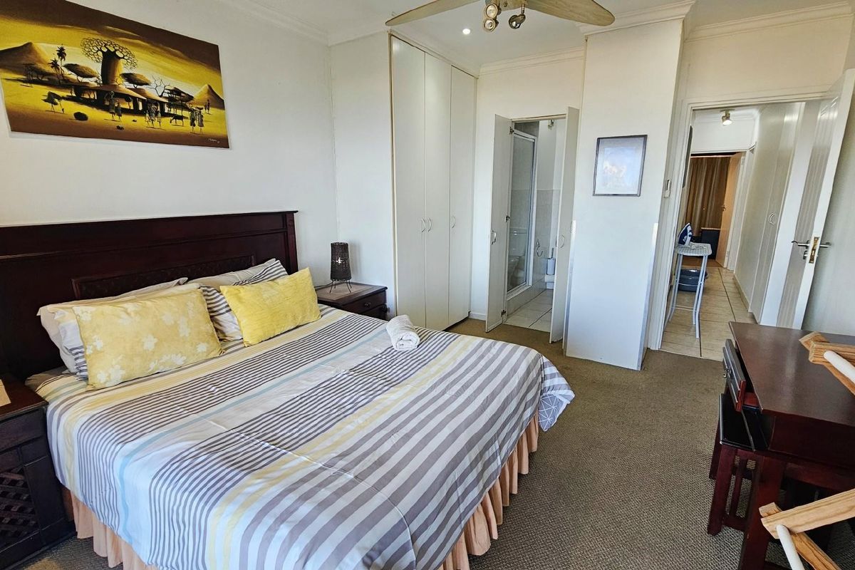 A bedroom featuring built-in cupboards, an en-suite bathroom, and neutral wall finishes, providing a functional and comfortable living space.
