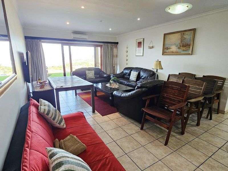 Spacious open-plan living and dining area featuring tiled flooring, recessed lighting, and large sliding glass doors providing access to the outdoor patio.