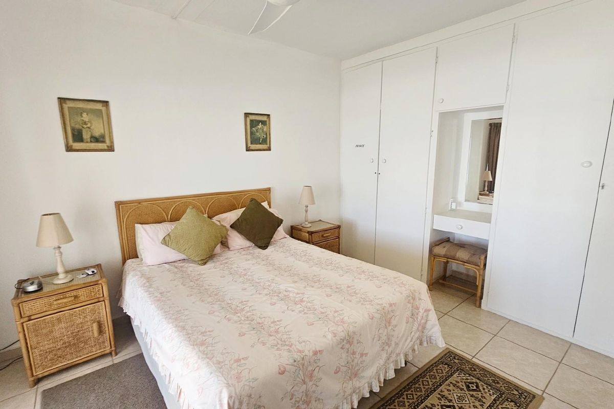 A bedroom featuring built-in cupboards with an integrated vanity unit and tiled flooring.