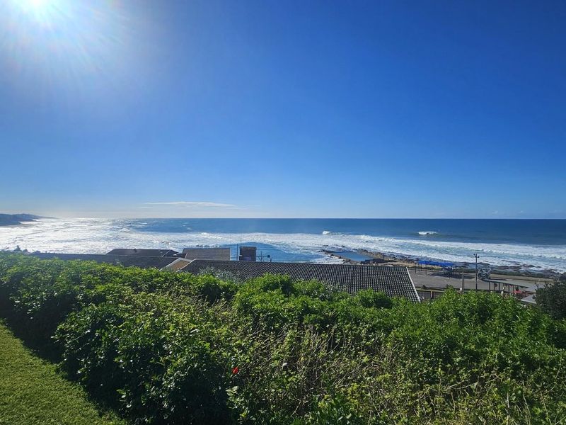 A scenic elevated view overlooking the coastline, ocean, and nearby beach infrastructure.