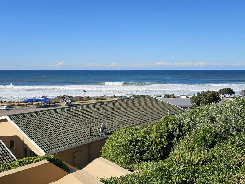 Elevated coastal view overlooking the ocean, nearby rooftops, and surrounding greenery, capturing a scenic seaside perspective.