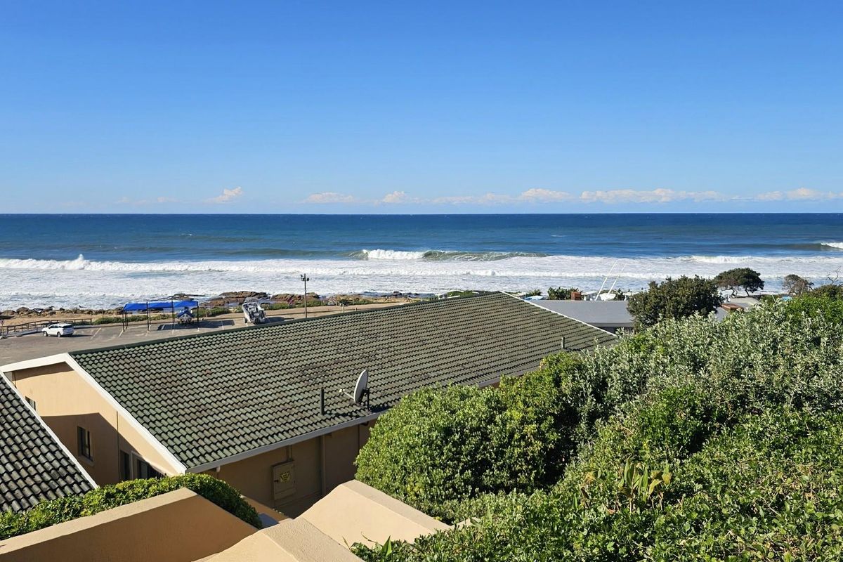 Elevated coastal view overlooking the ocean, nearby rooftops, and surrounding greenery, capturing a scenic seaside perspective.