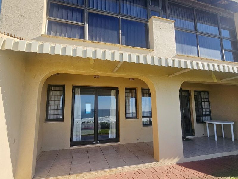 A covered ground-floor patio area featuring tiled flooring, arched structural supports, and direct access to the apartment through glass sliding doors.