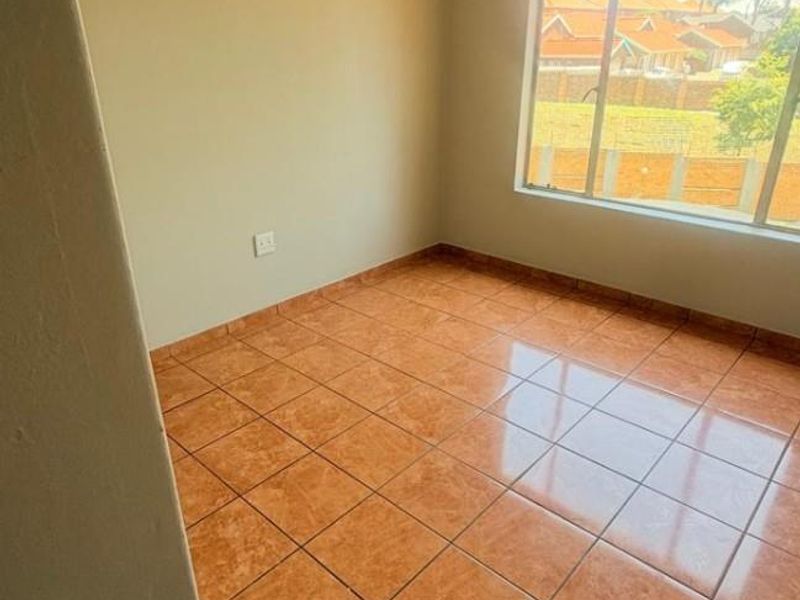 A bright, empty bedroom featuring neutral wall paint and durable ceramic tile flooring, offering a clean canvas for personalization.