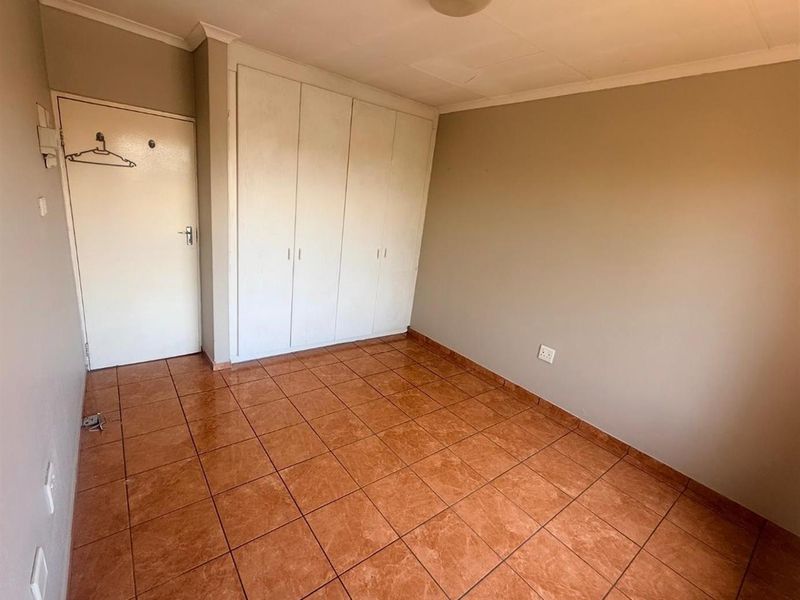 An empty bedroom featuring built-in cupboards and tiled flooring, offering a blank canvas for personalization.