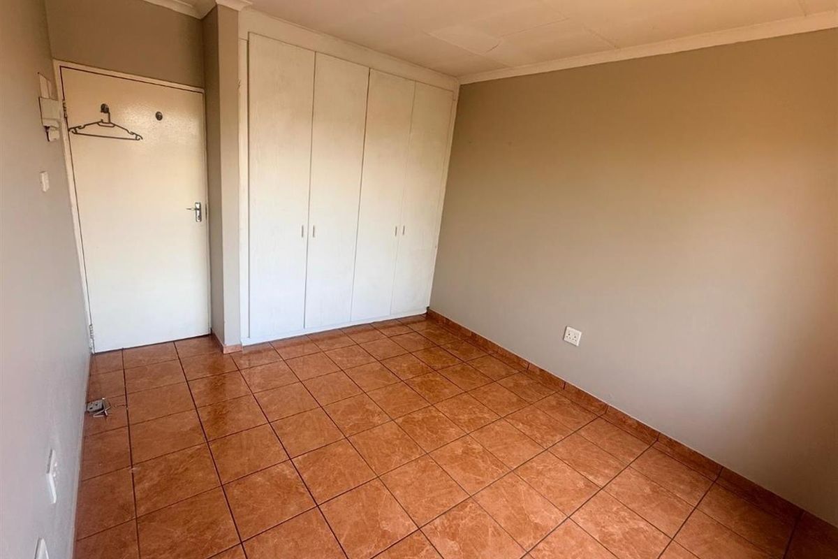 An empty bedroom featuring built-in cupboards and tiled flooring, offering a blank canvas for personalization.