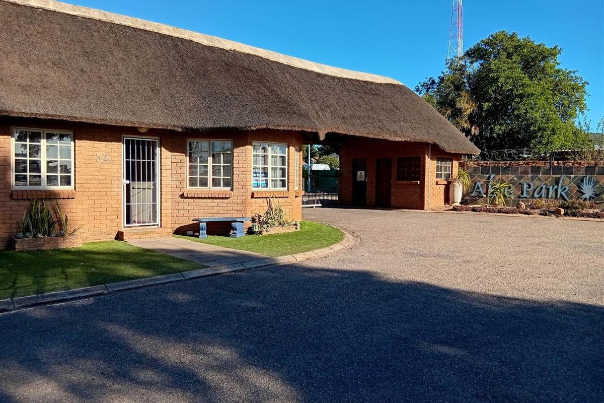 Front exterior view of the property featuring a traditional thatch roof, face brick construction, and a paved driveway entrance.