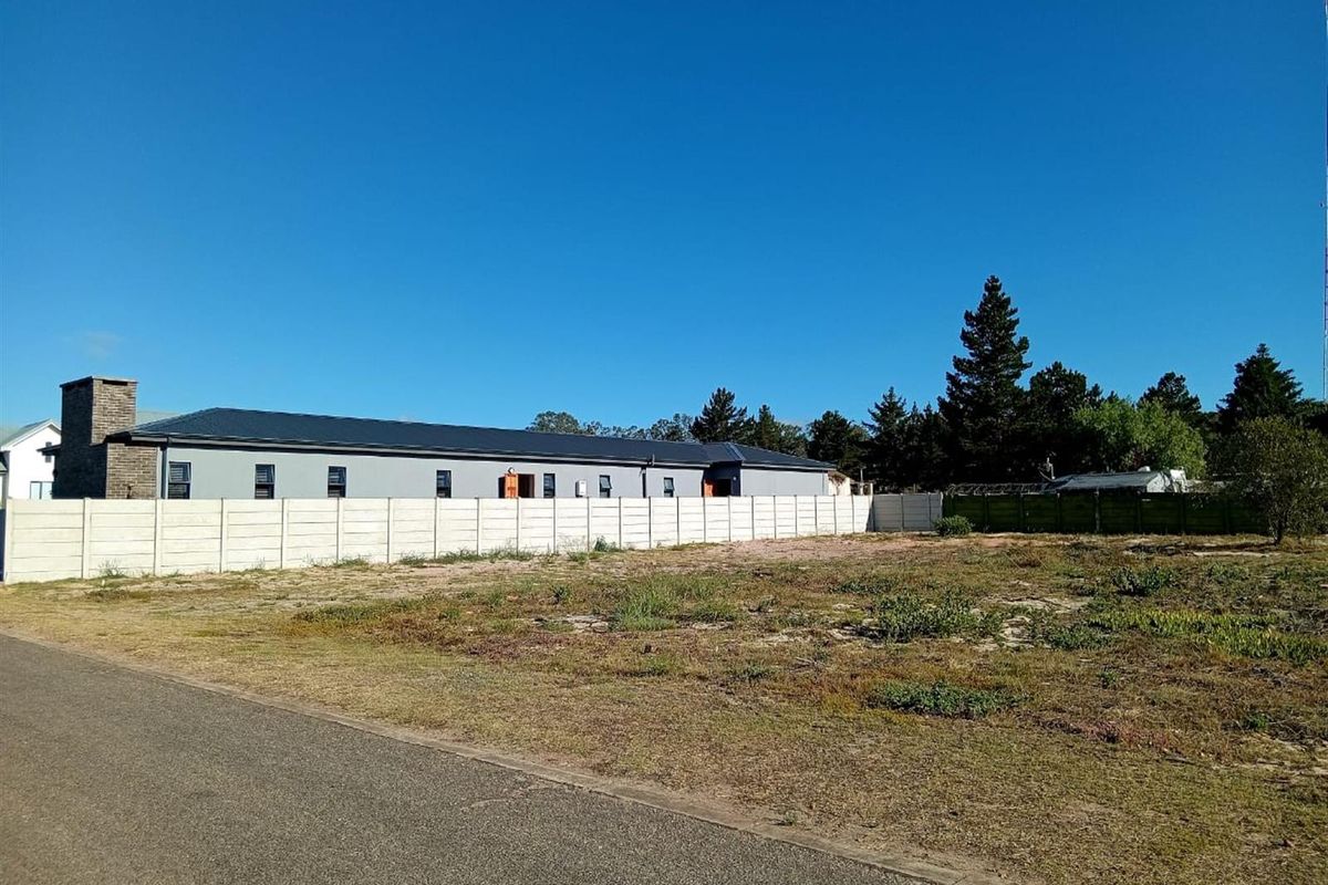 A vacant residential plot of land featuring a precast concrete boundary wall and direct access to an asphalt road.