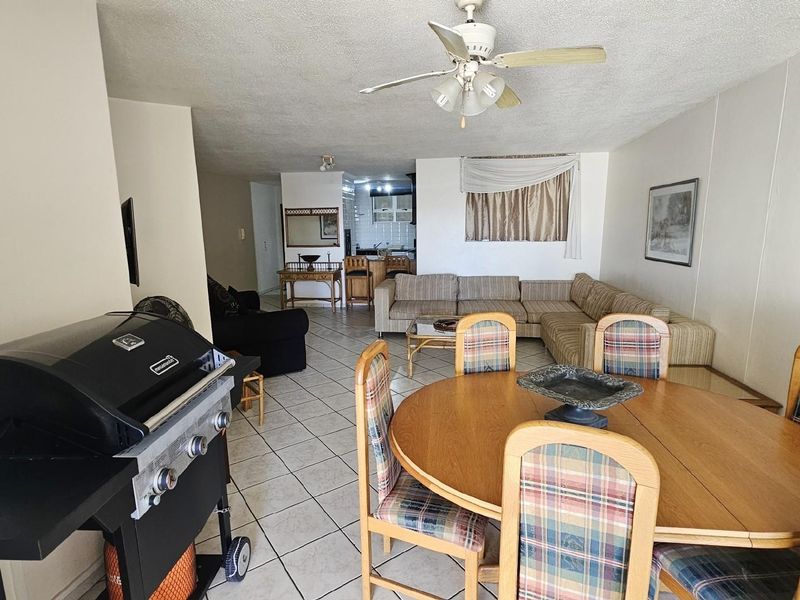 Open plan living and dining area featuring tiled flooring, a ceiling fan, and a direct view into the kitchen space.